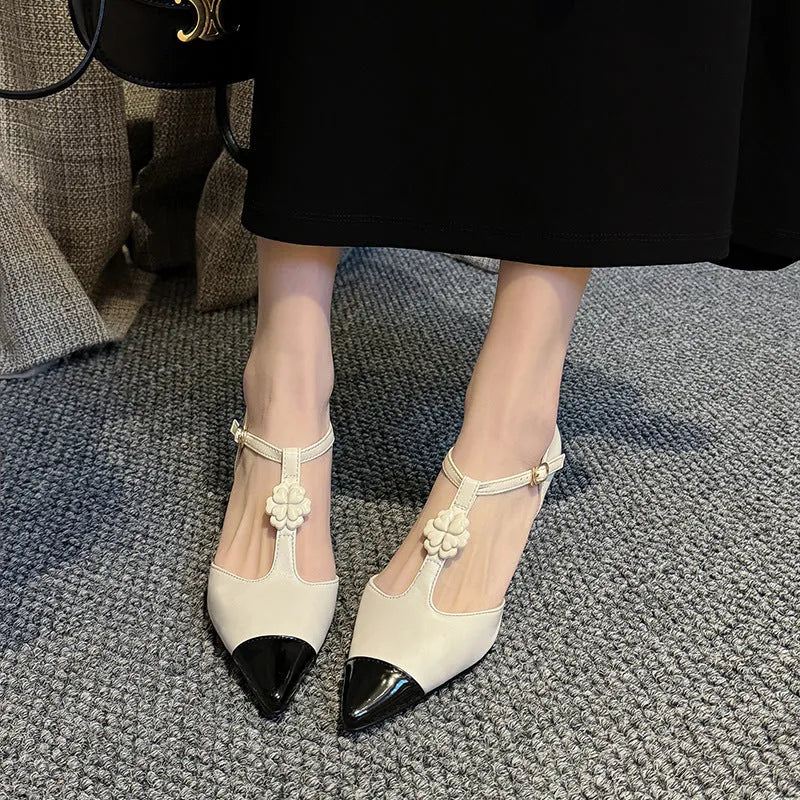 Women's black stiletto heel shoes with pointed toe, flower decoration, and buckle detail on sheepskin upper