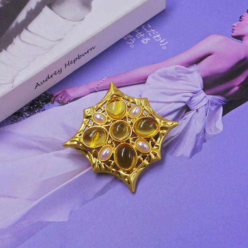 Close-up of a detailed baroque cross brooch with crystal accents on a zinc alloy base.