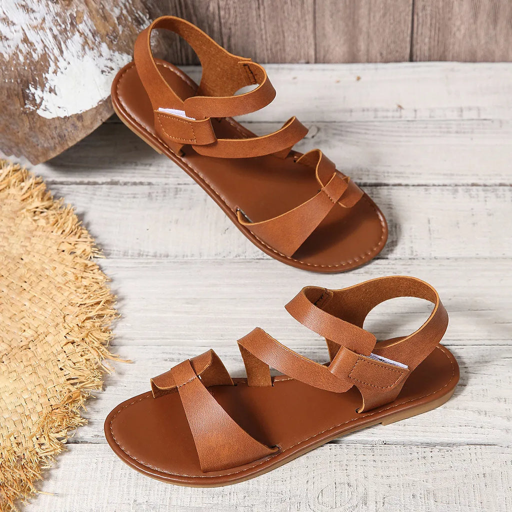 Women's black flat sandals with a Velcro strap closure, round toe, and rubber sole.