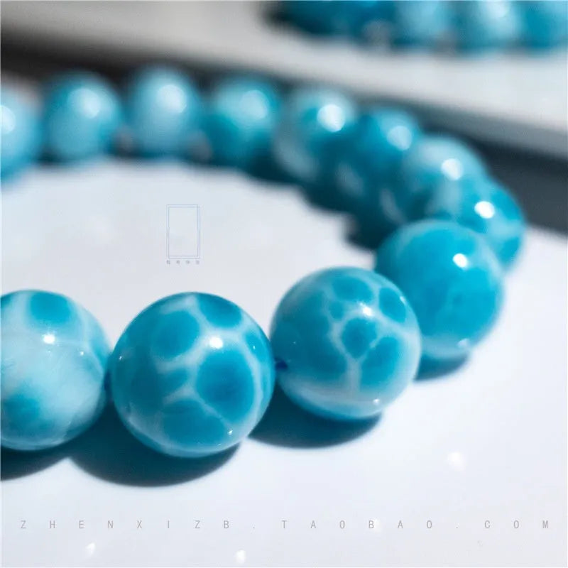 Blue handmade bodhi and pearl bracelet in Maillard style on a neutral background.