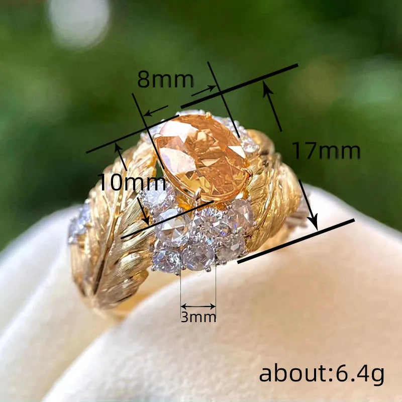 Gold-coloured copper ring with embossed feather design and yellow zircon stone inlay