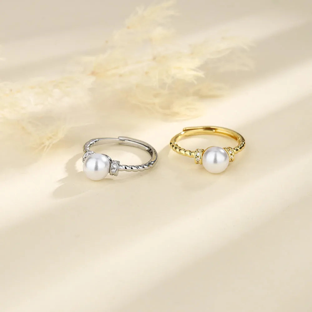 Adjustable geometric twist copper ring with a central pearl, shown in gold and silver colour options.