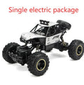 Large black or silver 4WD remote control climbing car on off-road terrain with wireless remote.