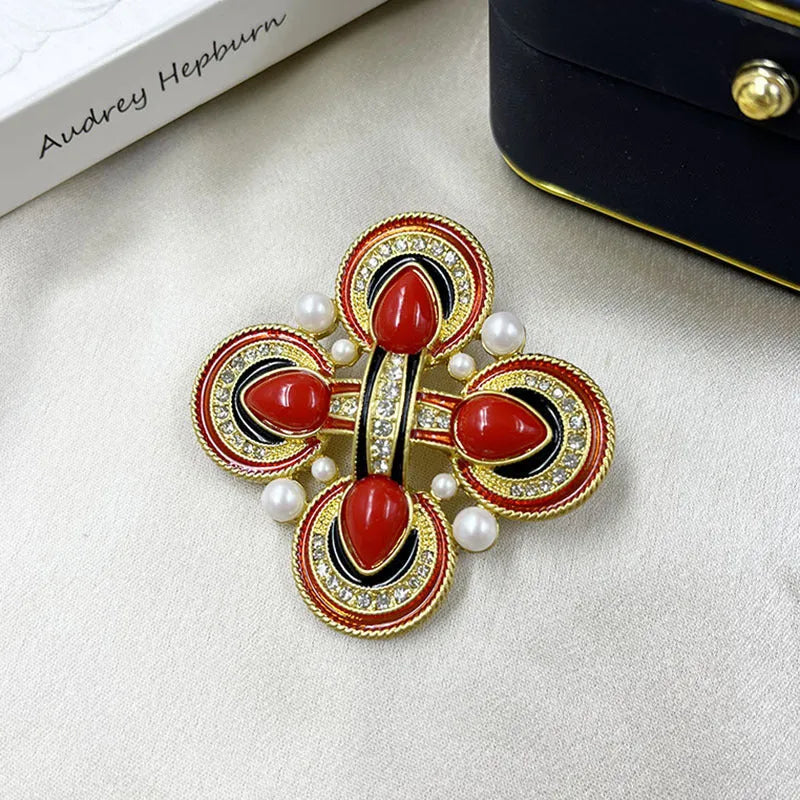 Close-up of a detailed baroque cross brooch with crystal accents on a zinc alloy base.