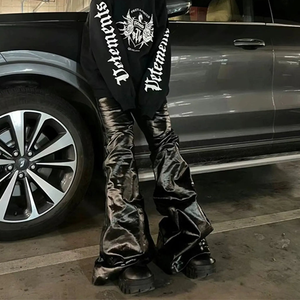 Black skinny jeans with a shiny patent leather coating and straight-leg cut on a denim background.