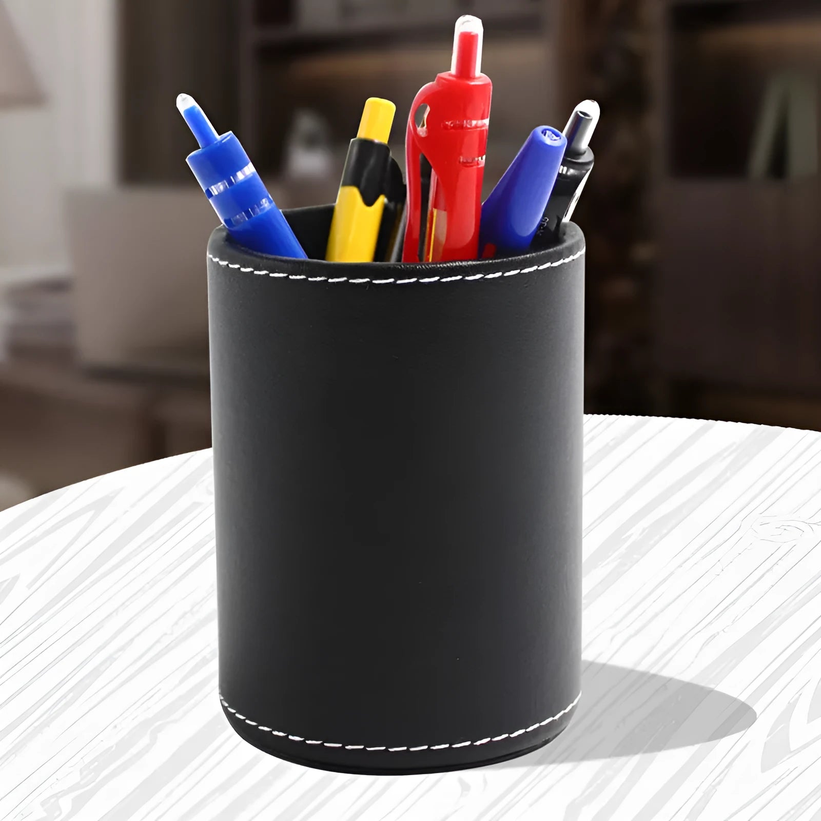 Round black leather pen holder with 8.0cm diameter on a desk