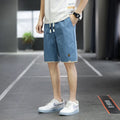 Men's straight loose fit casual beach shorts in green on a mannequin, showing elastic waistband.