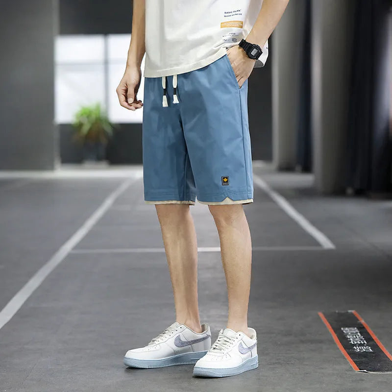 Men's straight loose fit casual beach shorts in green on a mannequin, showing elastic waistband.