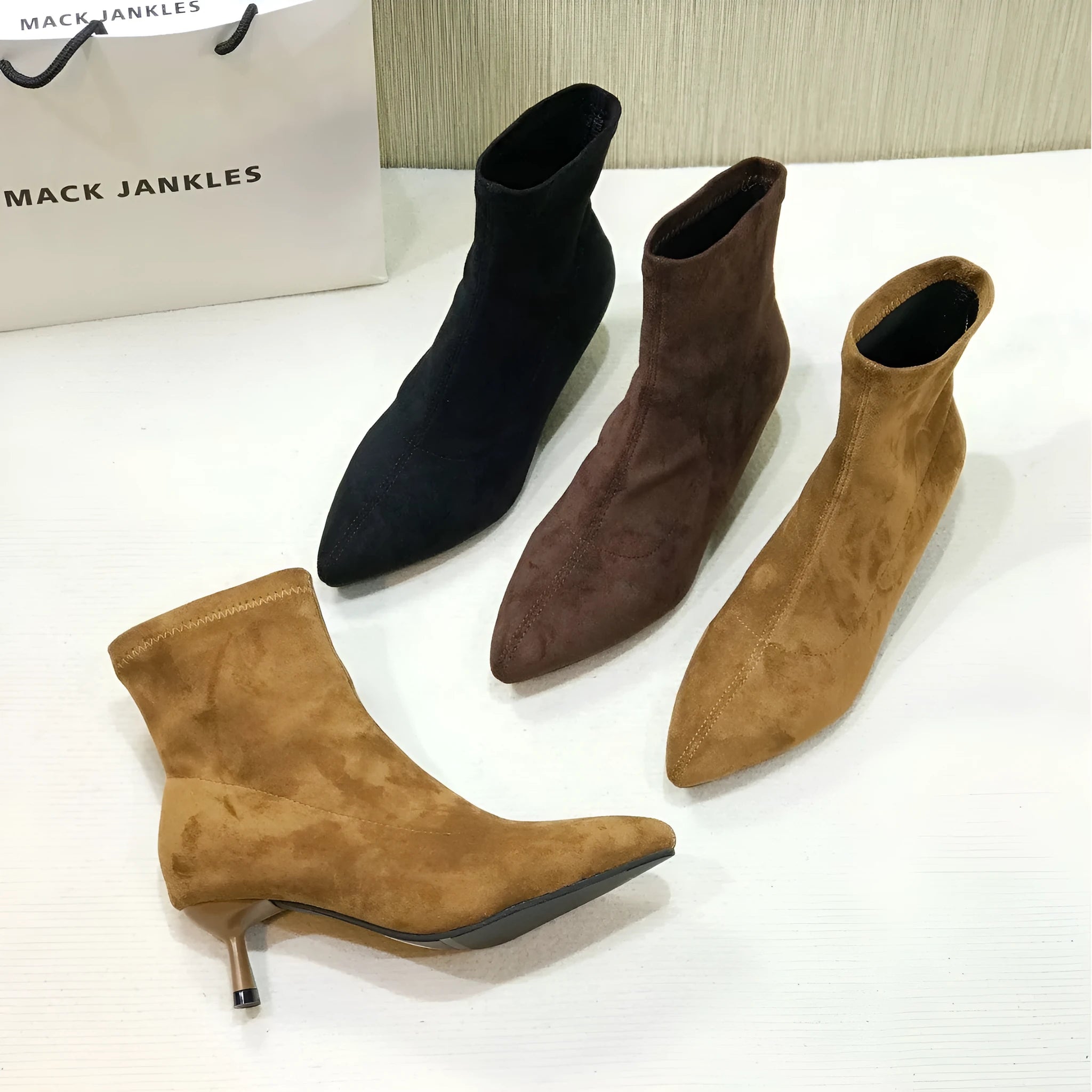 Women's black pointed toe ankle boots with a stiletto heel and mid-calf sock length.