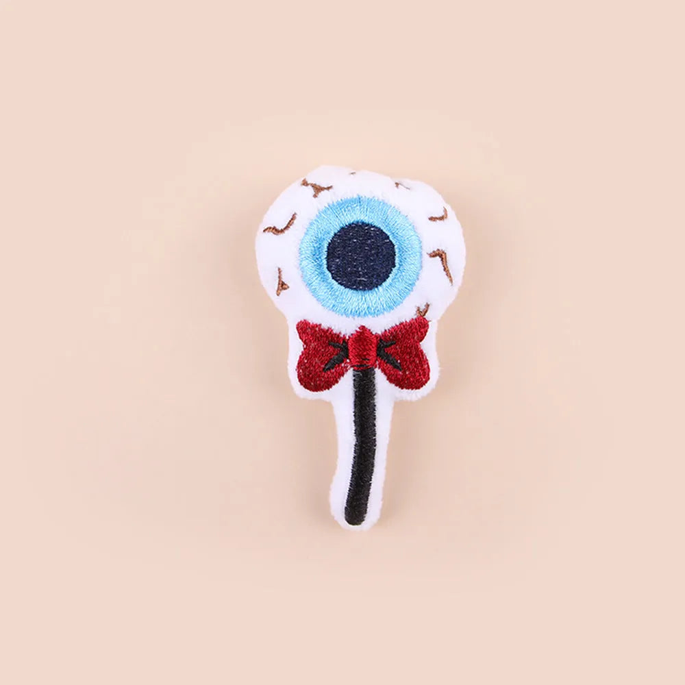 Plush cat wand toy with 27cm handle showing three interchangeable colourful heads: eyes, candy, and skull designs