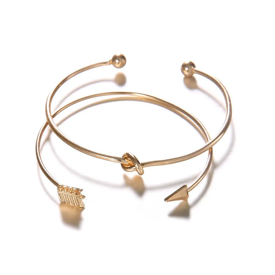 Gold-coloured women's vintage cuff bracelet with an arrow knot detail on an alloy band.