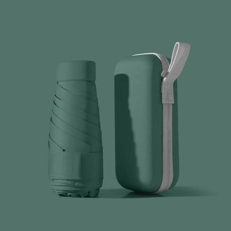 Ultra-light six-fold sun umbrella open, showing NC fabric canopy and rubber handle, next to its compact folded size in a capsule box.