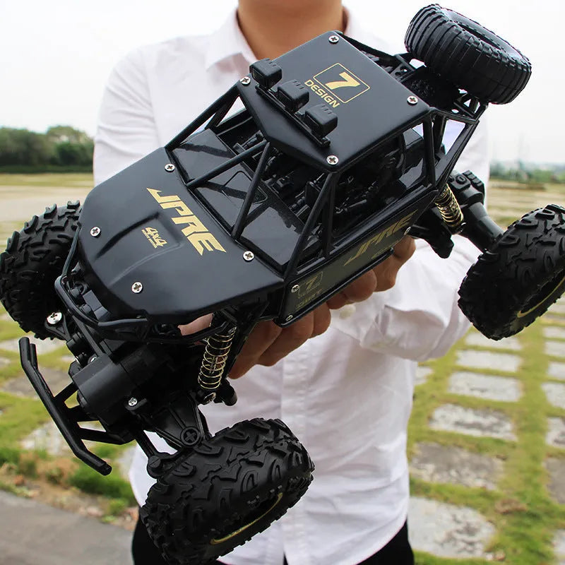 Large black or silver 4WD remote control climbing car on off-road terrain with wireless remote.