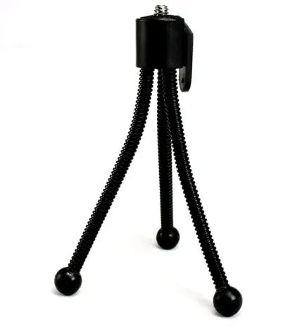 Small black iron mini tripod with ball head and folded legs on a table