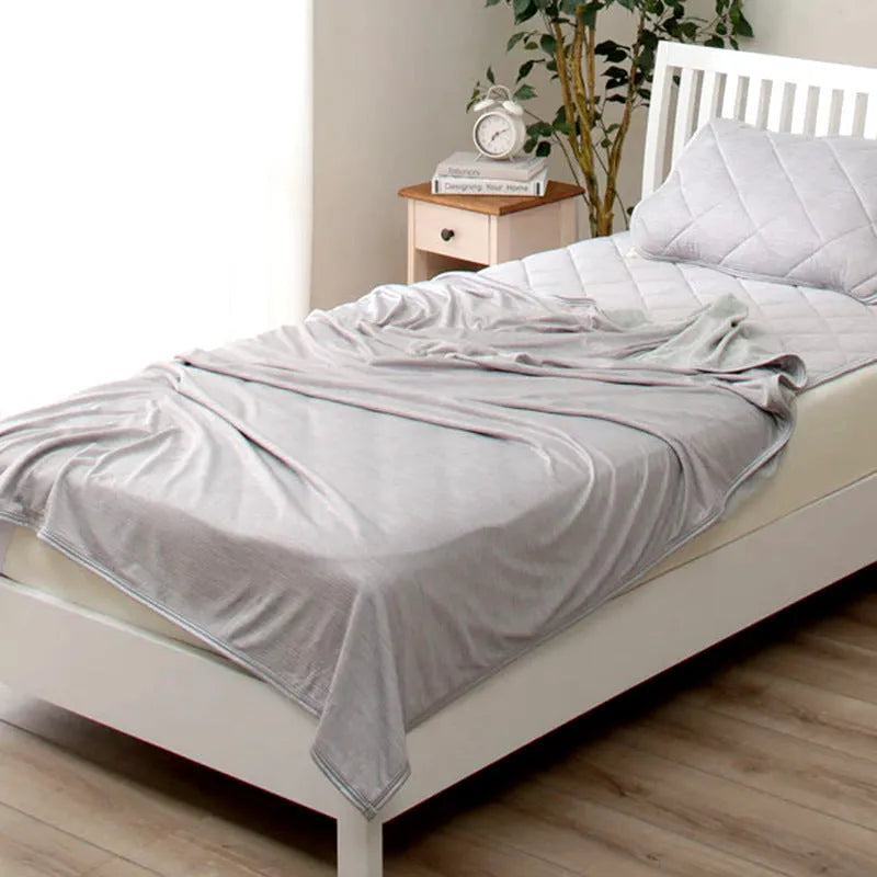 Blue Japanese cooling blanket with Q-Max fibres laid flat on a bed.