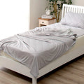 Blue Japanese cooling blanket with Q-Max fibres laid flat on a bed.