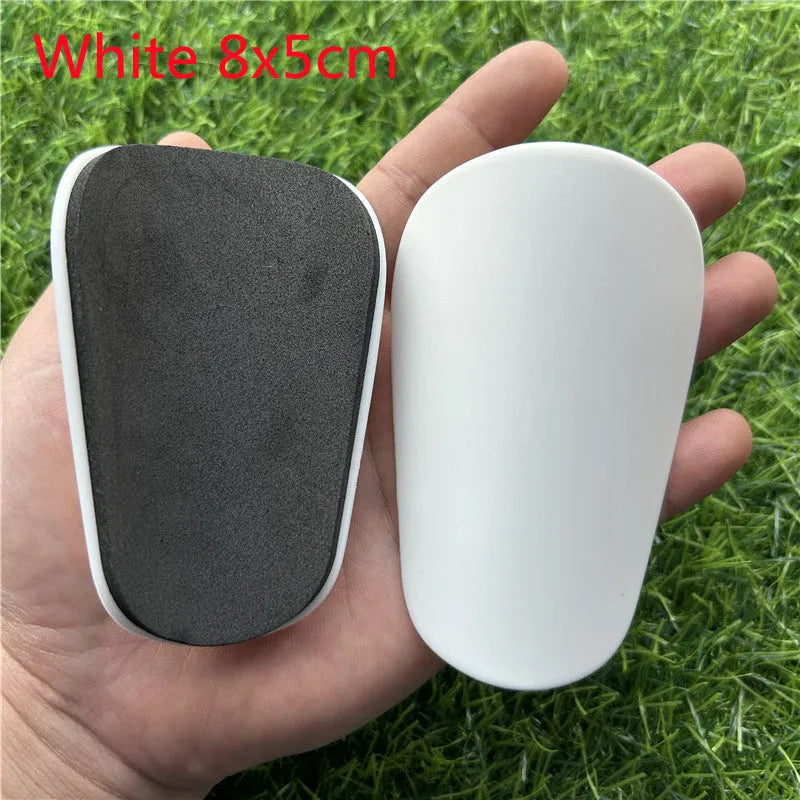 Pair of extra small black and white plastic football shin guards, size 8x5cm.
