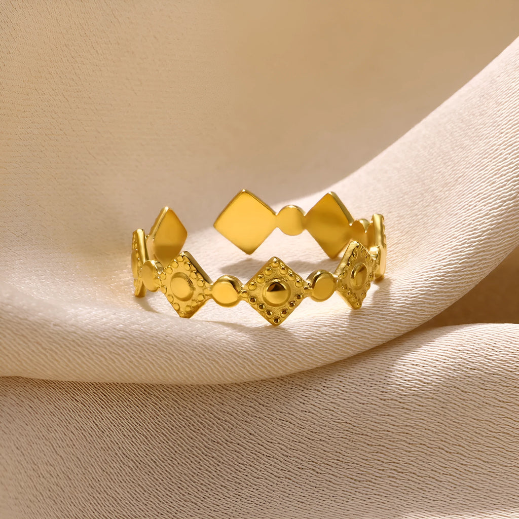 Geometric women's ring in titanium steel with a gold diamond finish on a plain background.