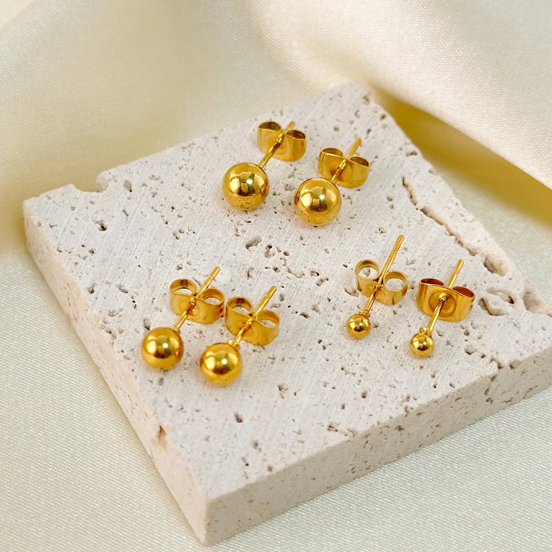 Stainless steel round ball stud earrings on a white background, showing gold and silver plated options.