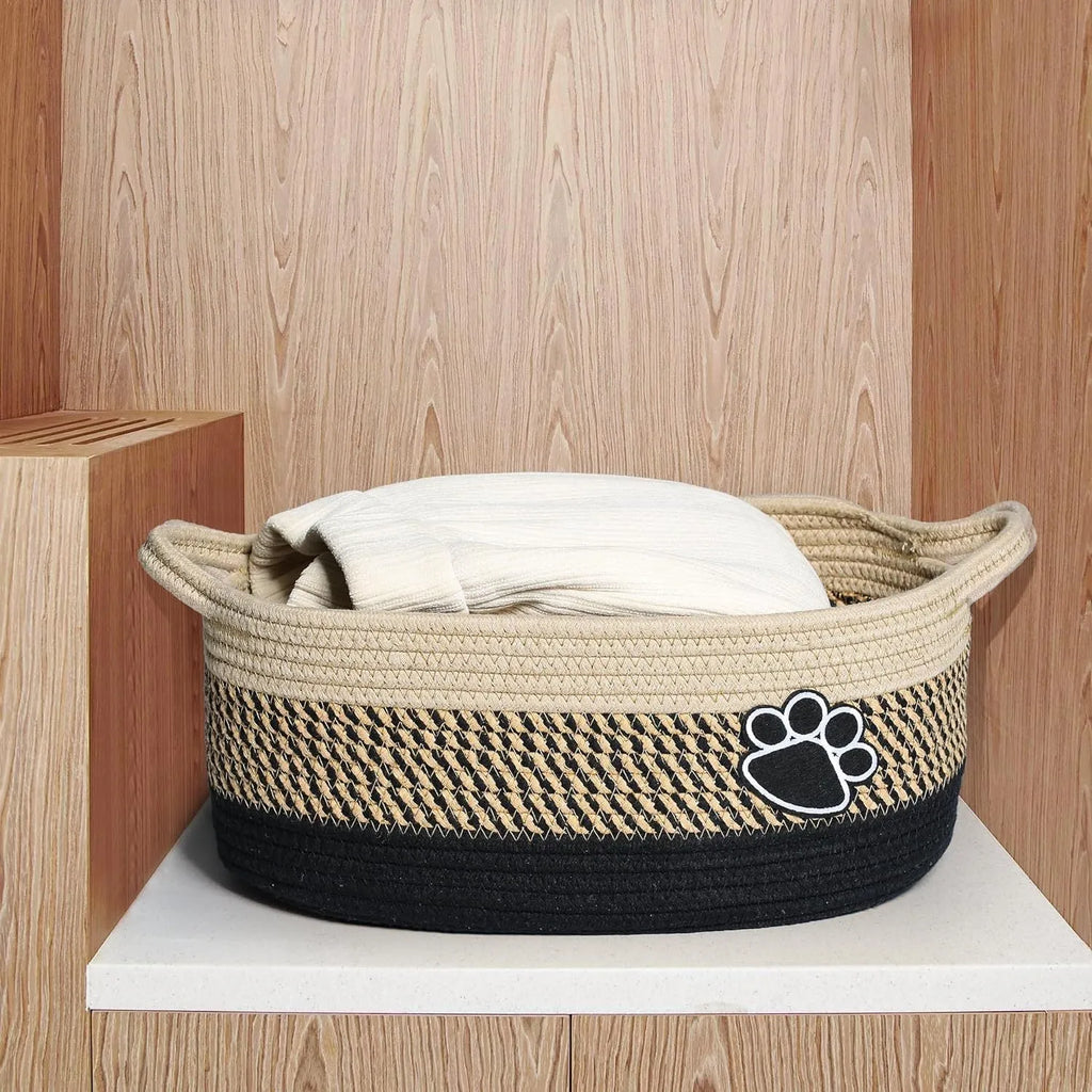 Light beige handmade cotton rope woven storage basket with a wooden handle on a table.