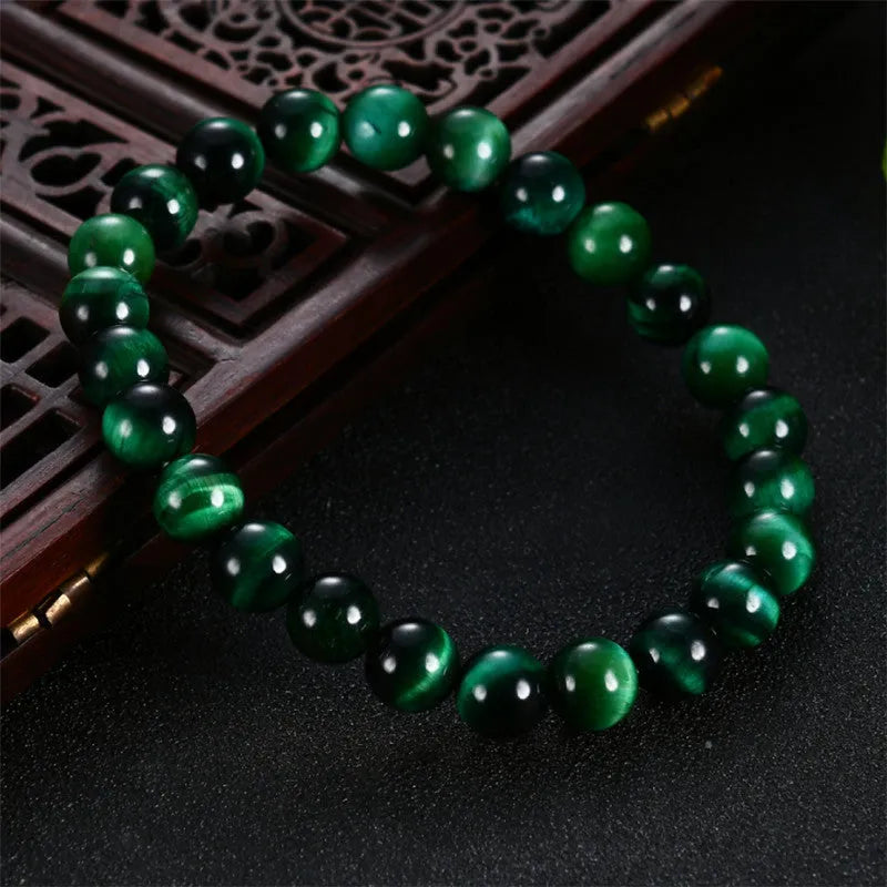 Green tiger eye stone geometric bead bracelet with adjustable closure on a wrist.