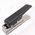 Gold metal guitar pick card cutter on a flat surface showing the punch head and metallic finish