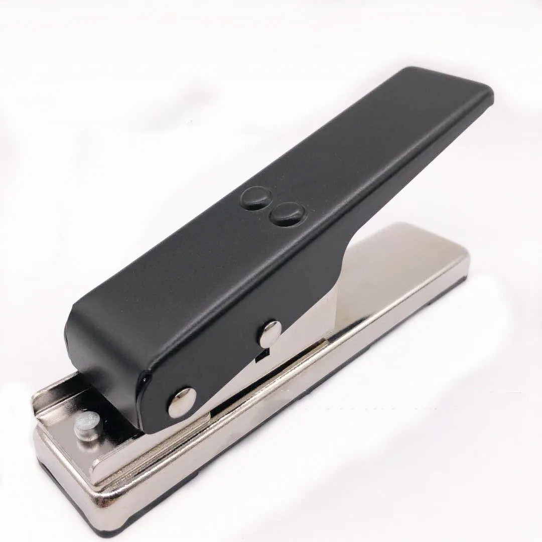 Gold metal guitar pick card cutter on a flat surface showing the punch head and metallic finish