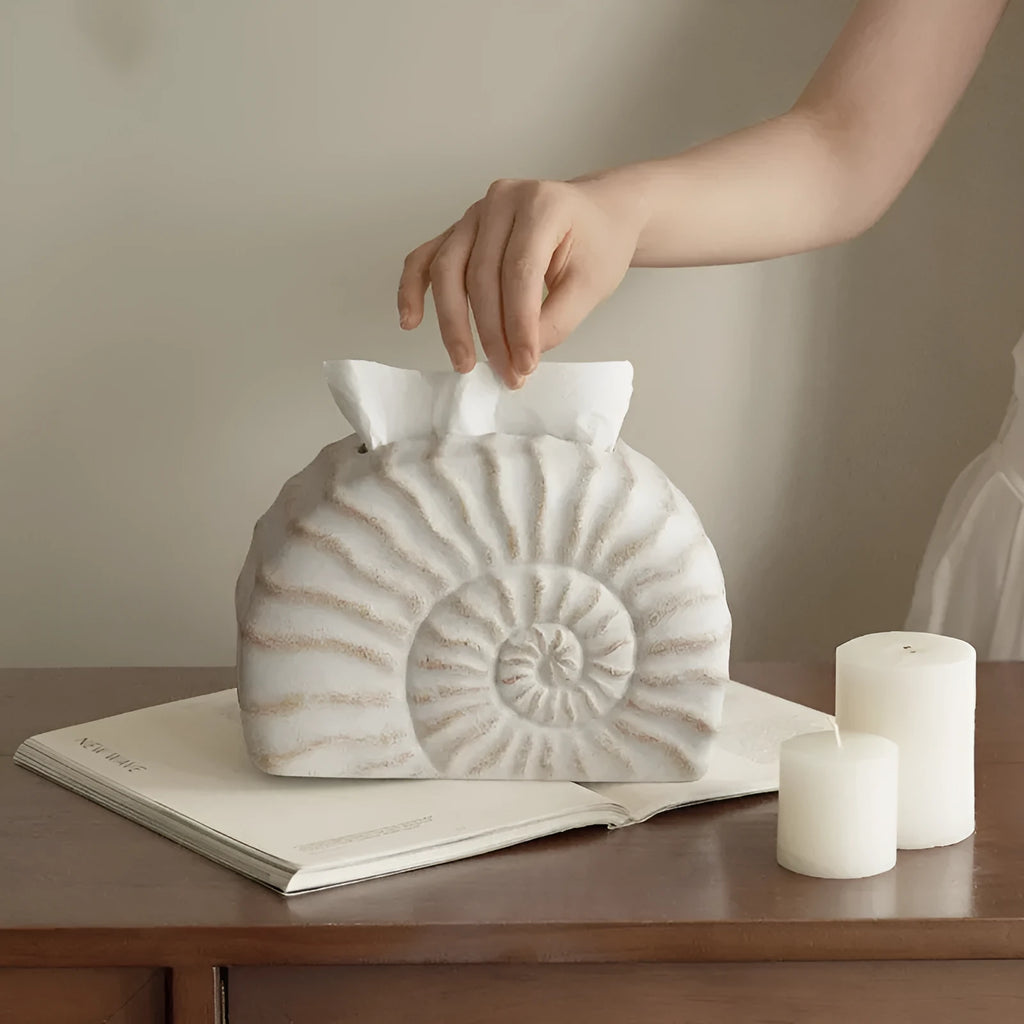 Solid resin conch-shaped tissue box cover in a natural colour on a table.