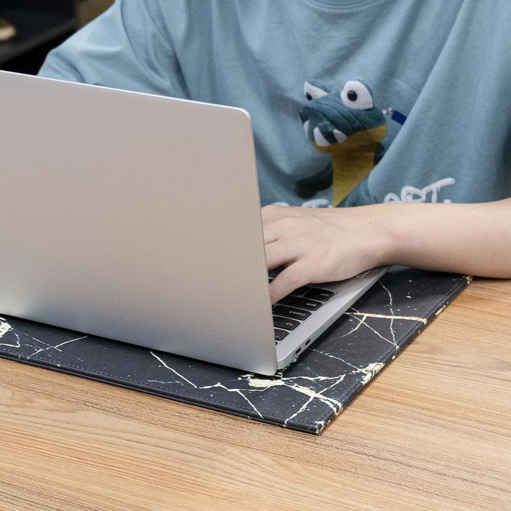 Heat-insulating laptop pad in black, gold, blue, and green colours on a desk