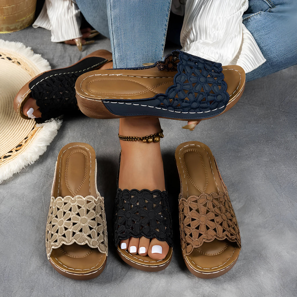 Women's black wedge beach slipper with floral cutouts and fish mouth toe shape on a rubber sole.