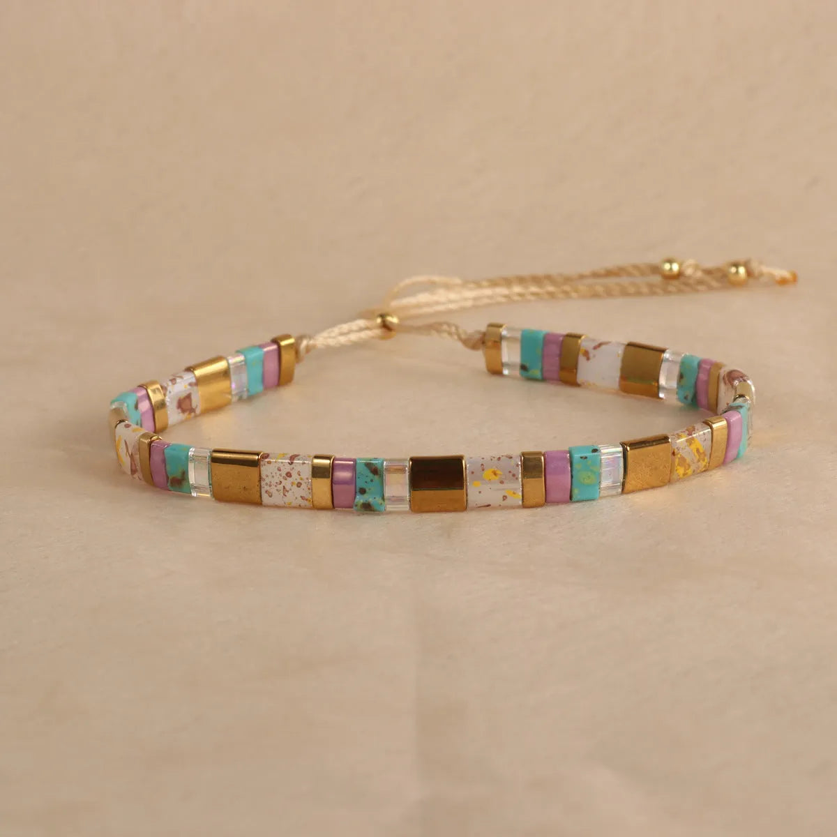 Adjustable pull beads bracelet with glass and coloured glaze beads in geometric and round shapes