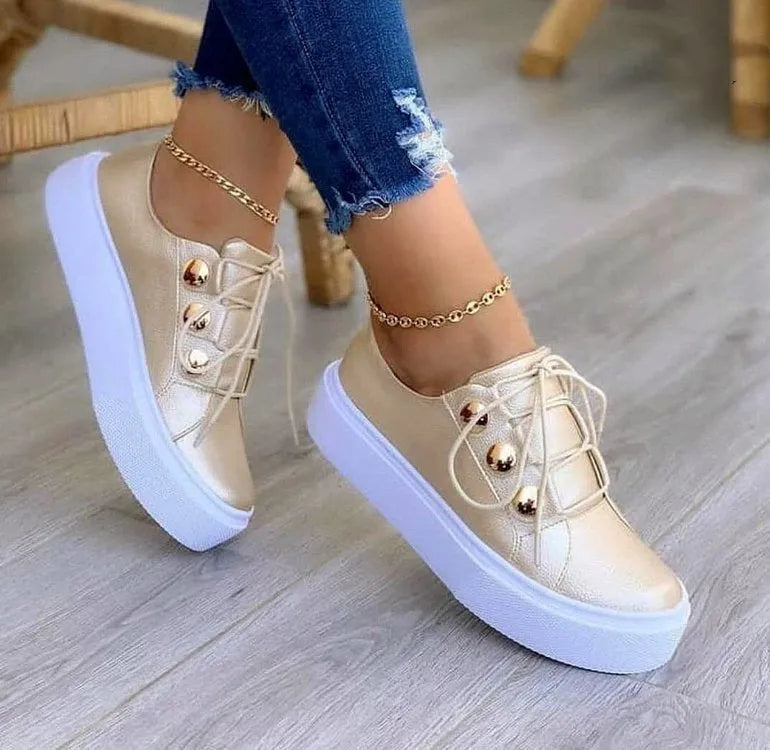 Women's white lace-up casual sneaker flats with silver rivet details on the round toe and low-top design.