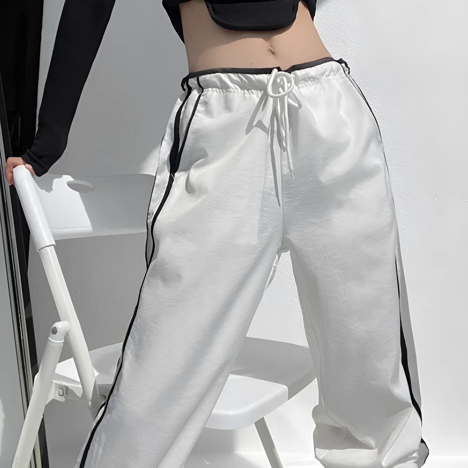 Women's navy blue loose straight-leg pants with white contrast ribbon parallel bars detail and low waist.
