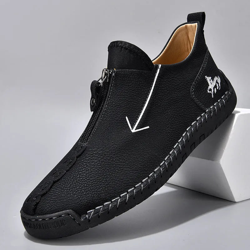 Men's black leather boots with a front zipper and round toe, showing hand-stitched sole detail.