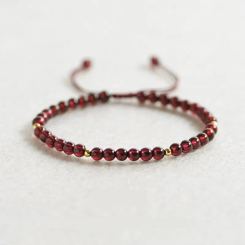 Women's geometric braided rope bracelet with freshwater pearls, amethyst, pomegranate, and red beads.