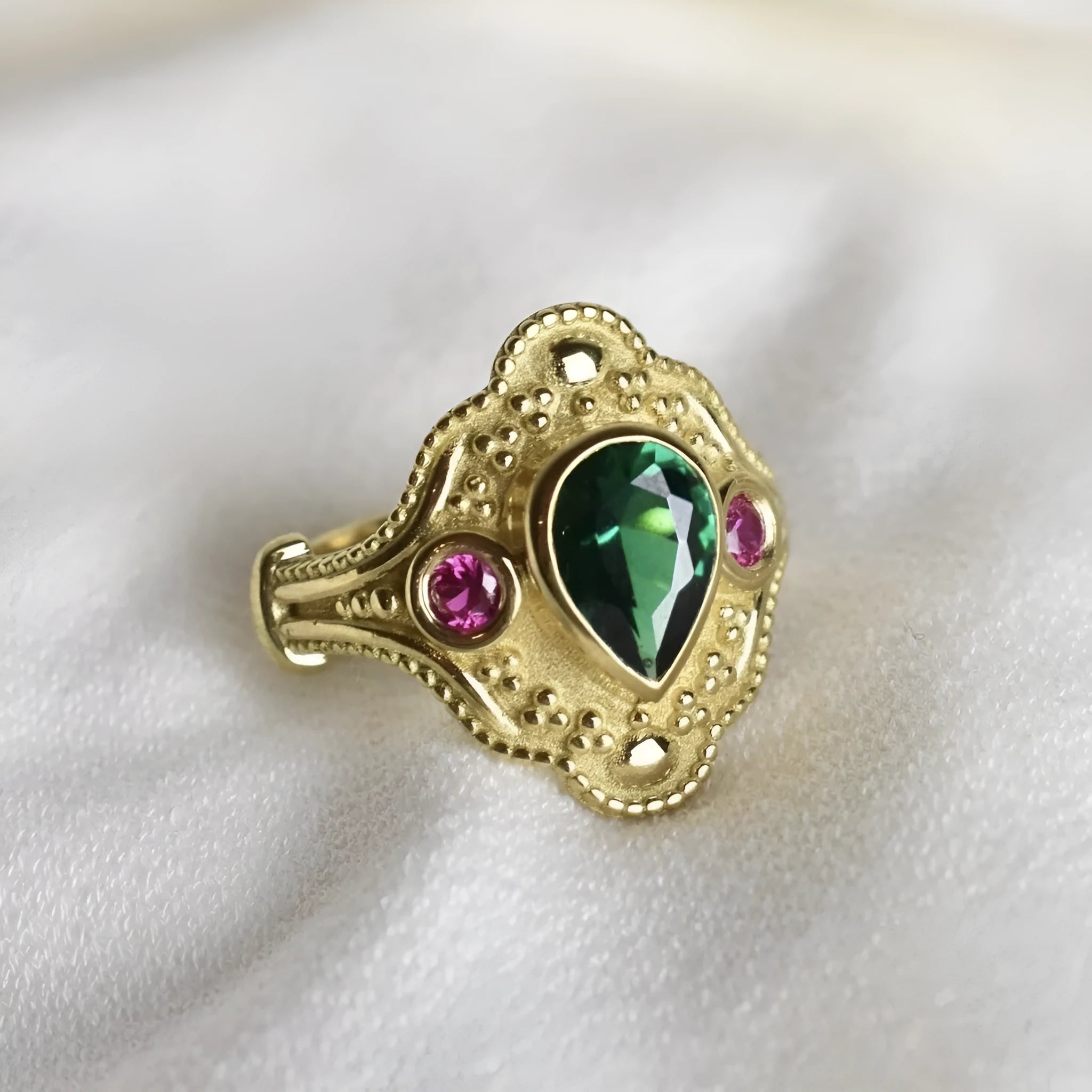 A gold-coloured women's ring with a geometric shape on a plain background.