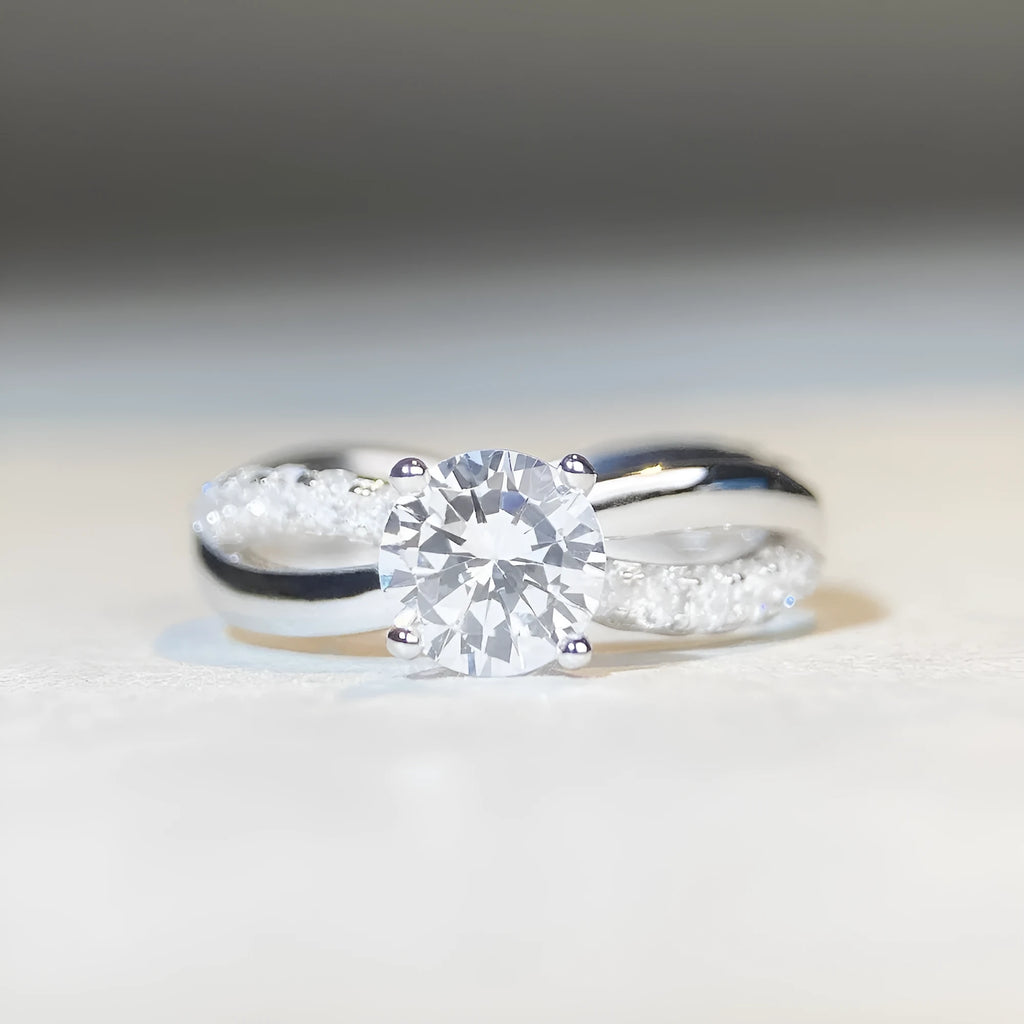 A geometric silver ring with a twisted band and a 1 carat moissanite stone in a four-claw setting.