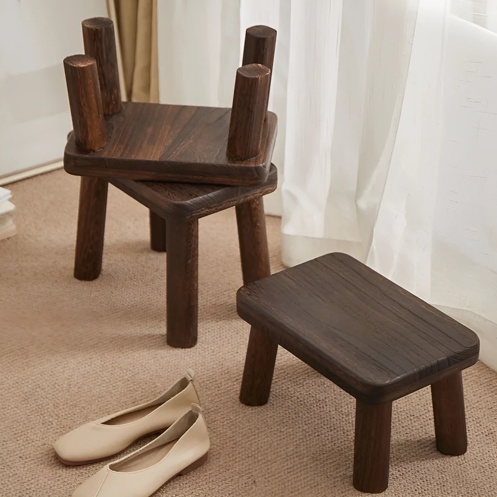 Solid wood distressed finish shoe changing stool with bracket legs in a living room setting.