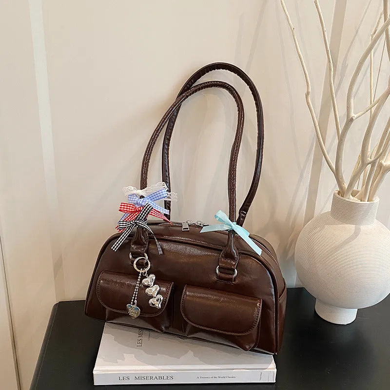 Brown PU leather retro pillow bag for women with a flap closure and double shoulder strap.
