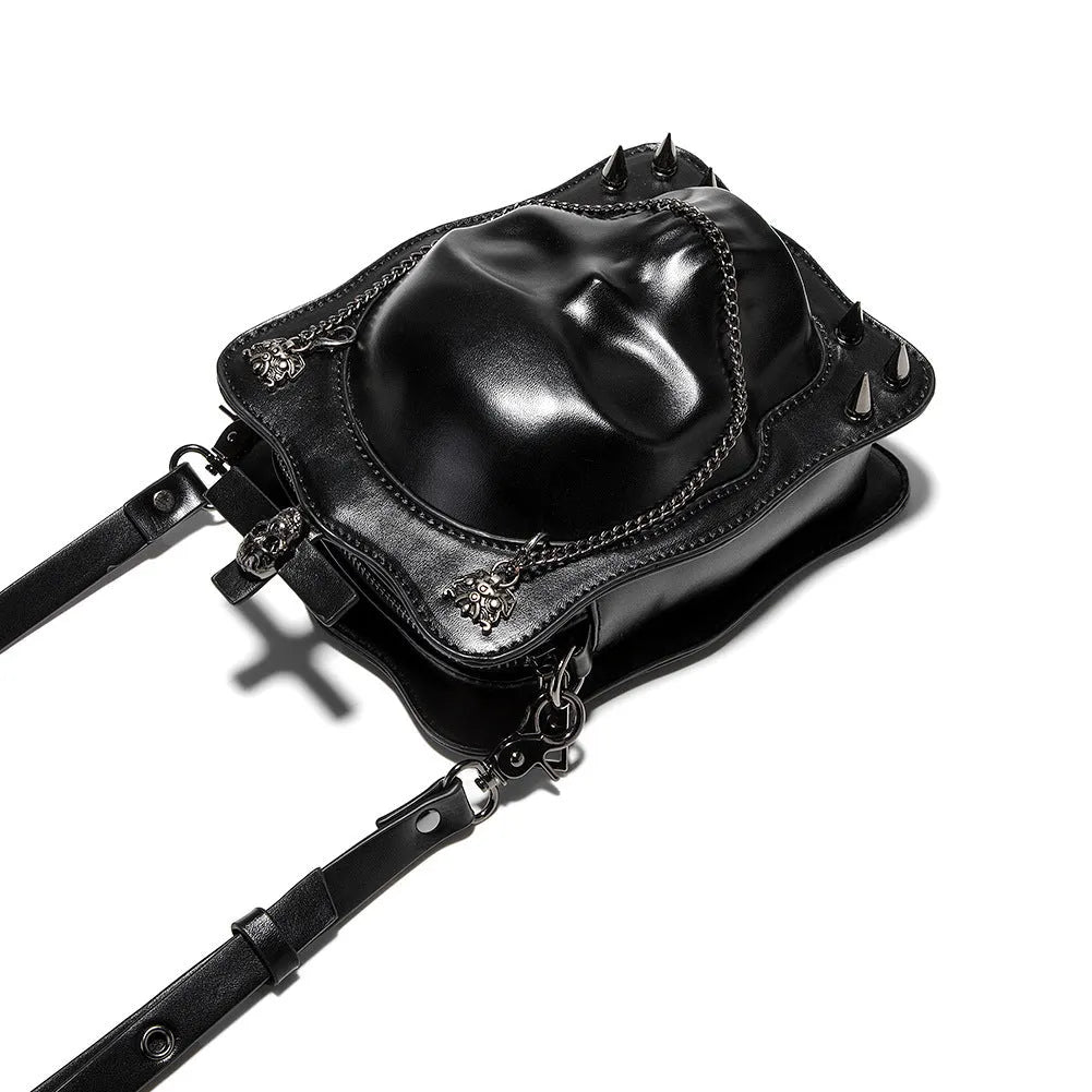 Black mini square crossbody bag with skull embossing, chain detail, and metal rivets on a vertical PU leather messenger bag.