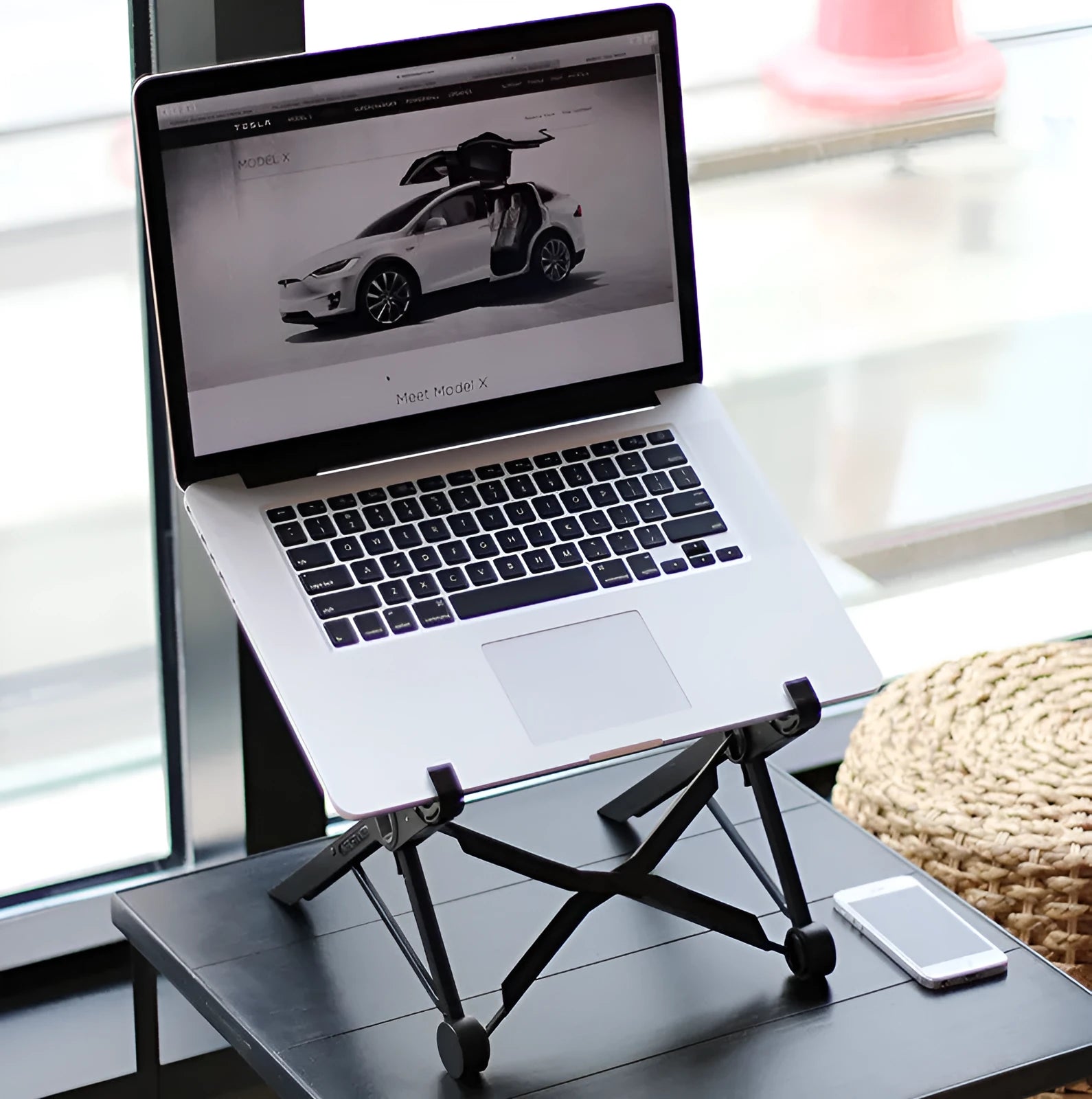 Black folding laptop stand made of reinforced nylon, shown in a compact folded size.