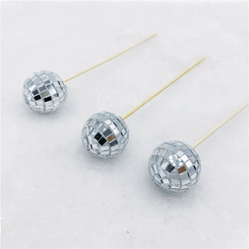 Glass disco ball cake decorations with wooden sticks in multiple sizes on birthday cake