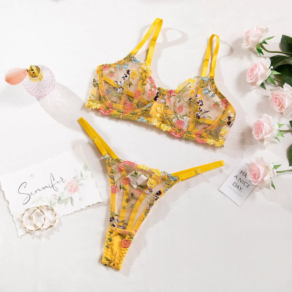 Women's floral print polyester bikini lingerie set on a hanger, showing colour options of skin, purple, black, yellow, and pink.