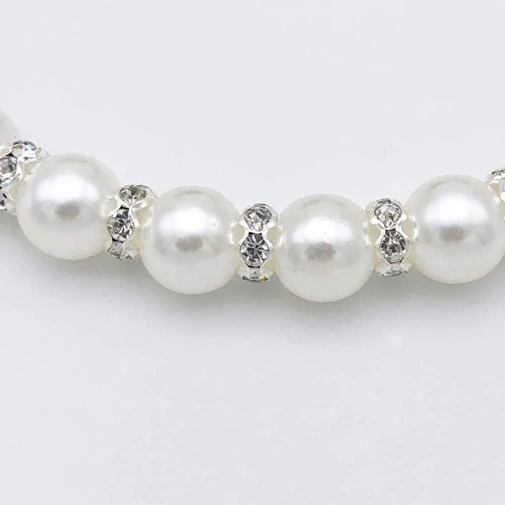 Adjustable blue pearl and rhinestone dog necklace collar with ribbon bow on a small dog.