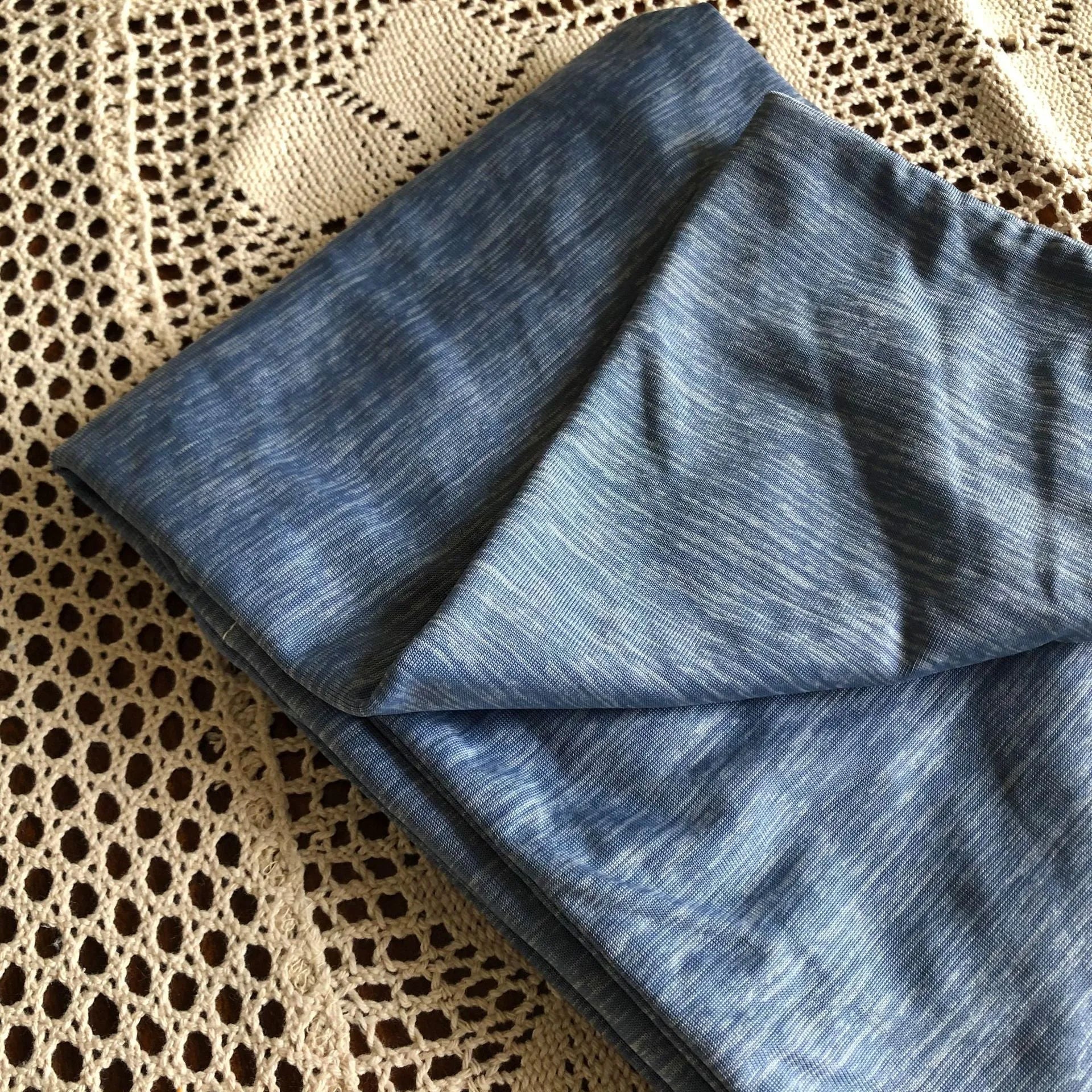 Blue Japanese cooling blanket with Q-Max fibres laid flat on a bed.