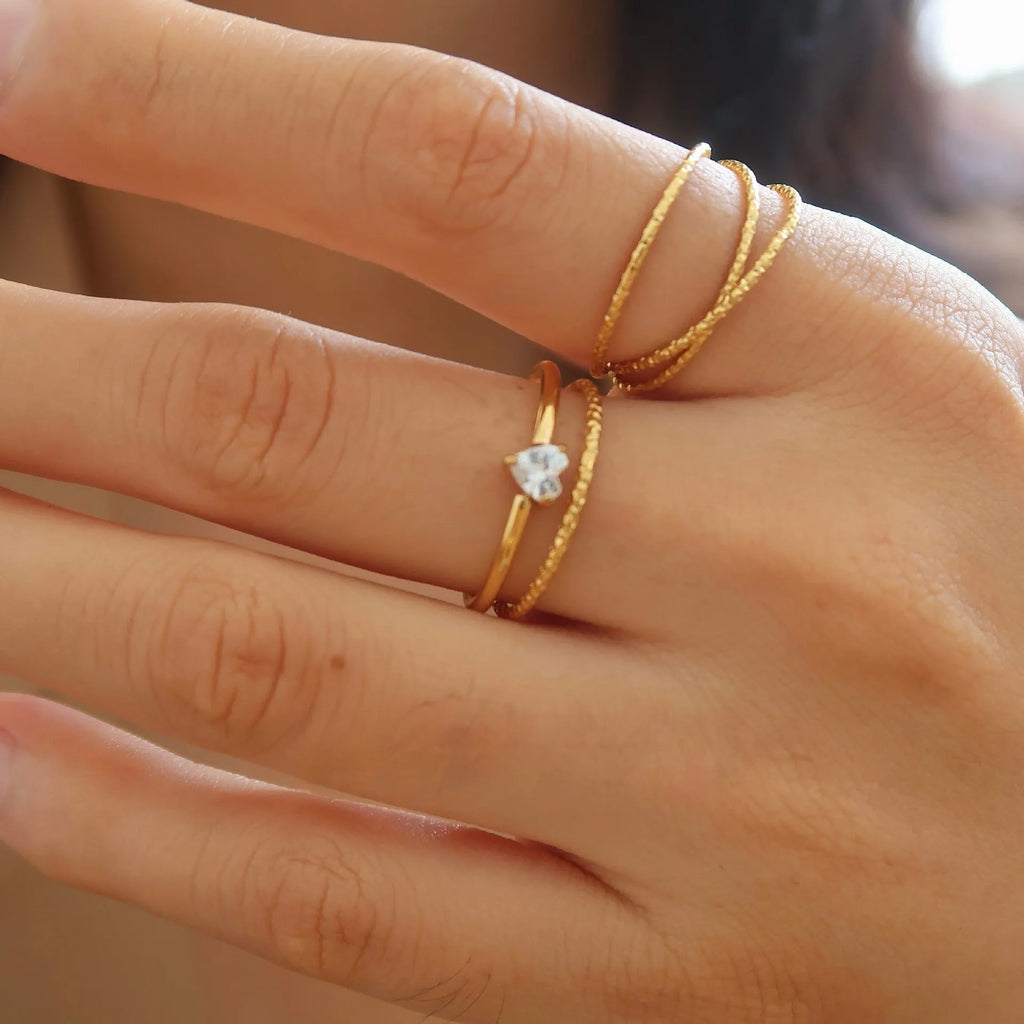 Golden electroplated stainless steel ring showing heart and oval shape designs on a hand.