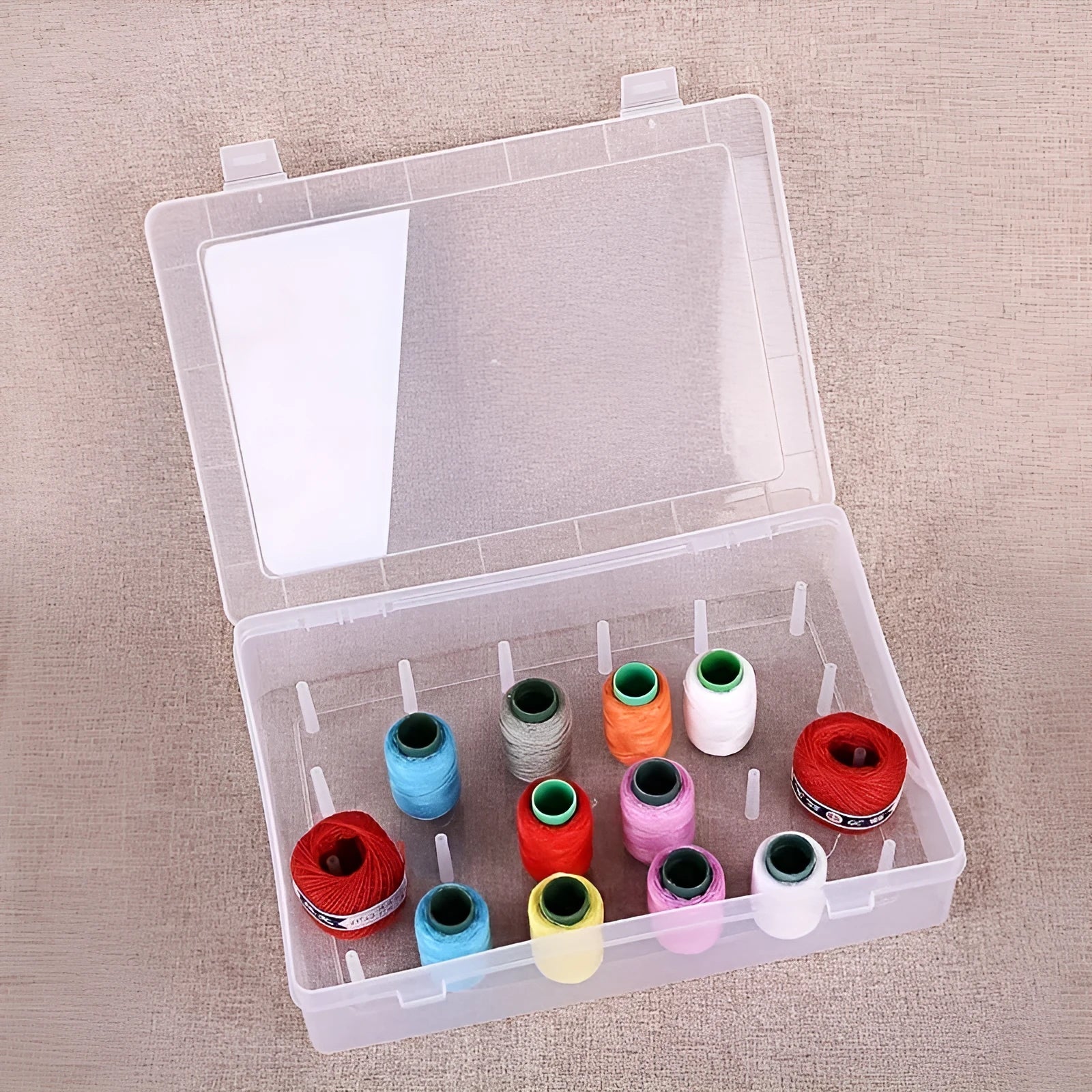Transparent plastic sewing storage box with 42 removable compartments for organising threads and needles.