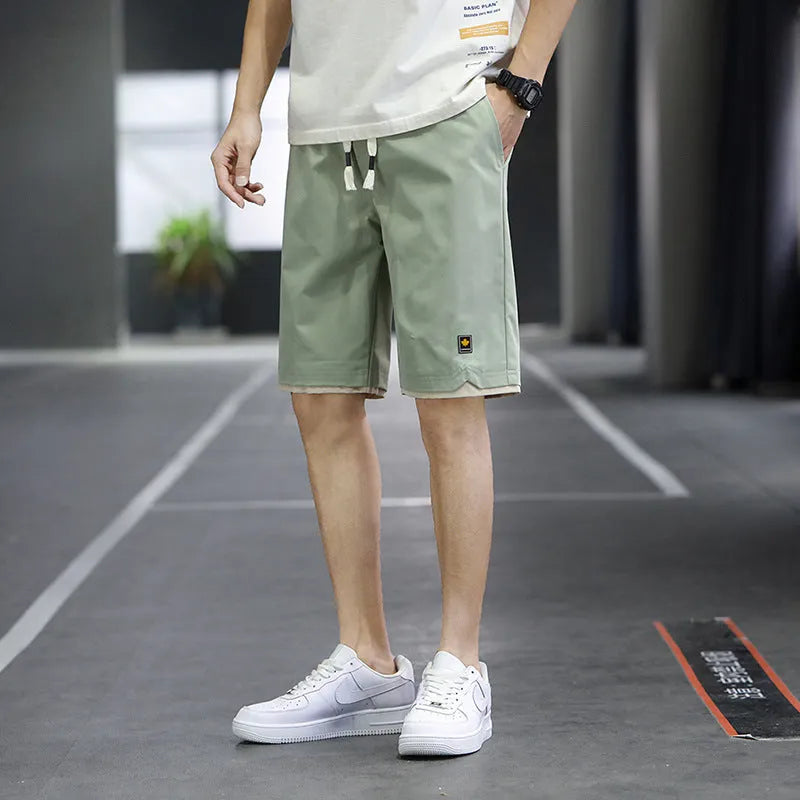Men's straight loose fit casual beach shorts in green on a mannequin, showing elastic waistband.