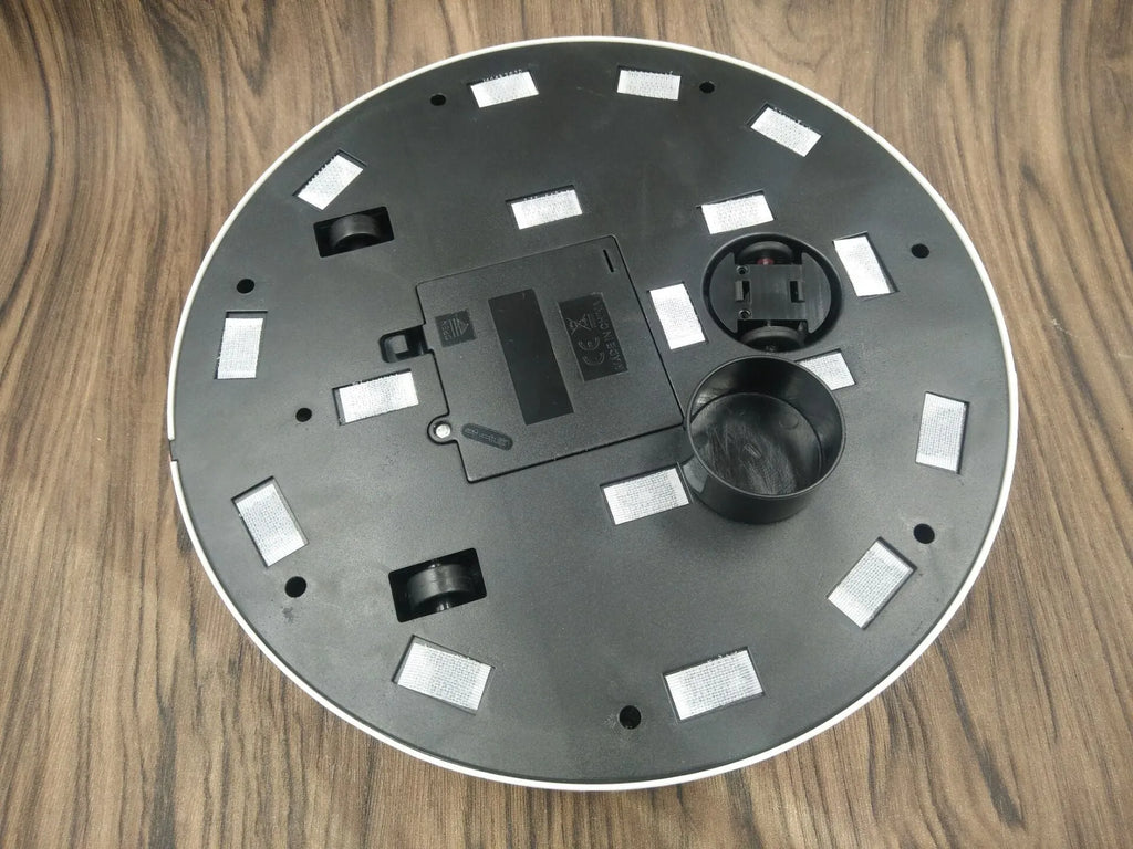 Black AC automatic sweeping robot vacuum cleaner on a wooden floor.