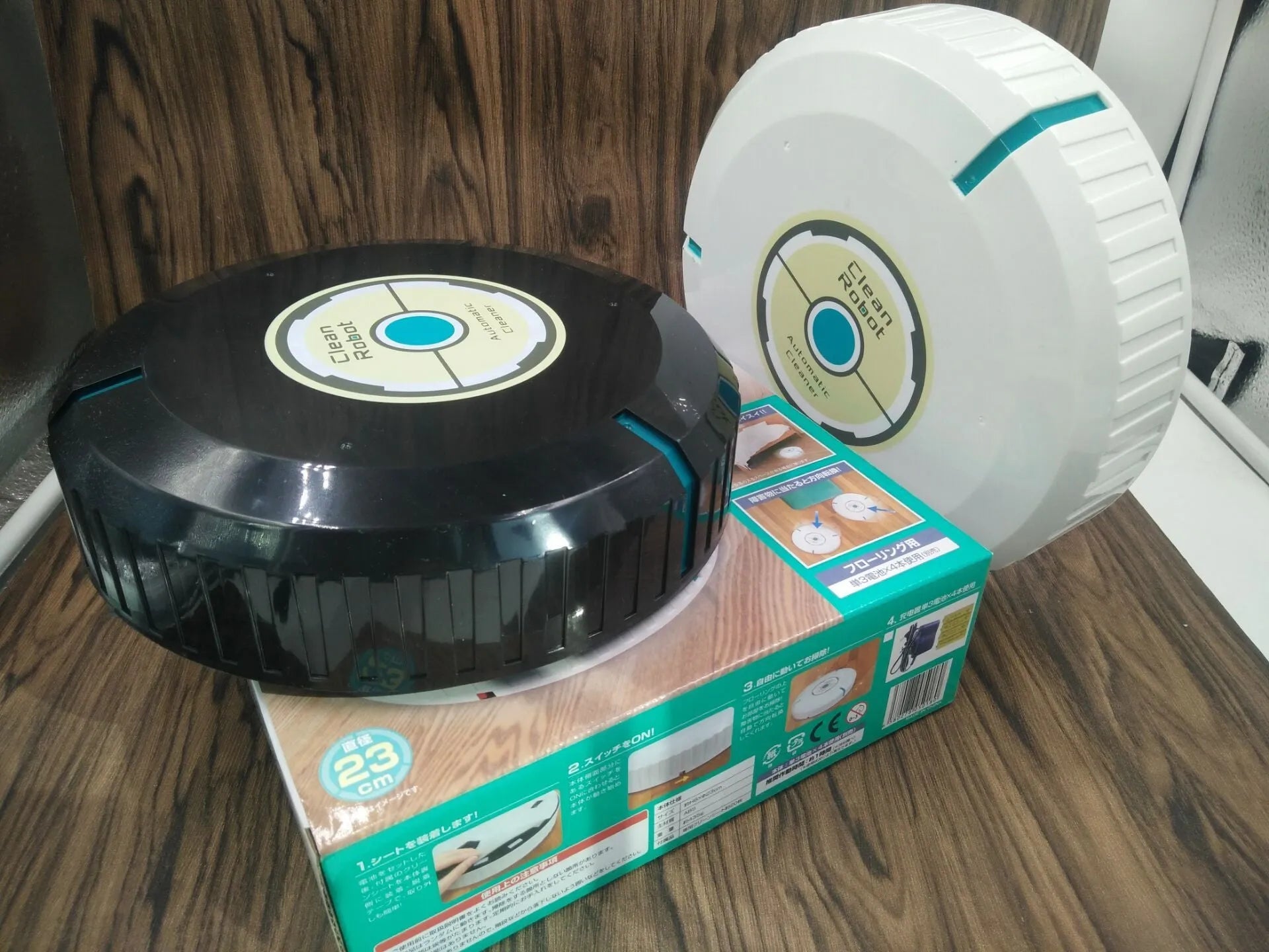 Black AC automatic sweeping robot vacuum cleaner on a wooden floor.